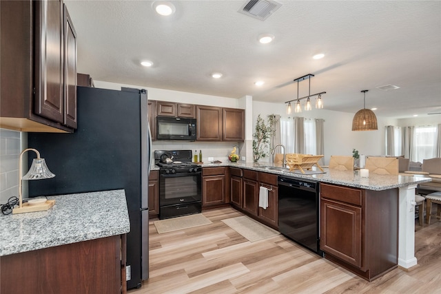 4335 Leyland Brook Ln, Houston, TX 77068 - kitchen featuring black appliances, a peninsula, a sink, light wood finished floors, and decorative backsplash