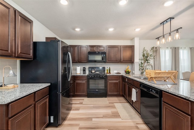 4335 Leyland Brook Ln, Houston, TX 77068 - kitchen with black appliances, light wood-type flooring, decorative backsplash, a peninsula, and light stone countertops