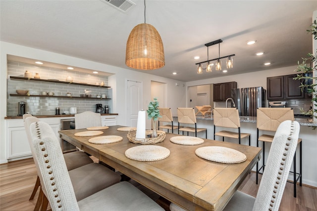 dining space featuring beverage cooler, recessed lighting, light wood-style flooring, and visible vents
