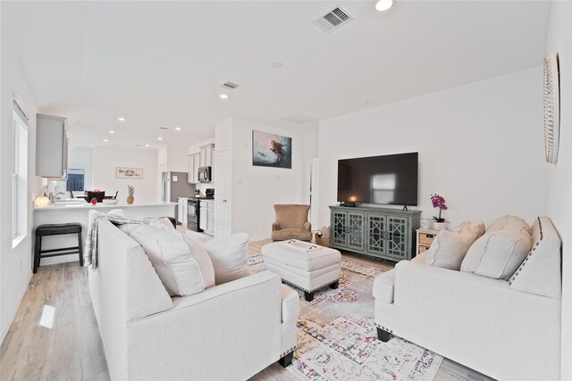 living room featuring recessed lighting, light wood-style floors, and visible vents