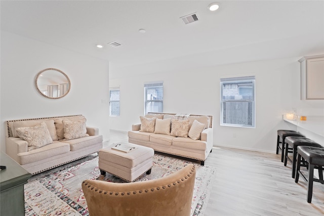 living room featuring light wood-style flooring, visible vents, and plenty of natural light