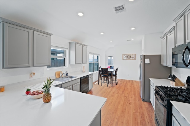 kitchen with light countertops, black appliances, gray cabinetry, visible vents, and a sink