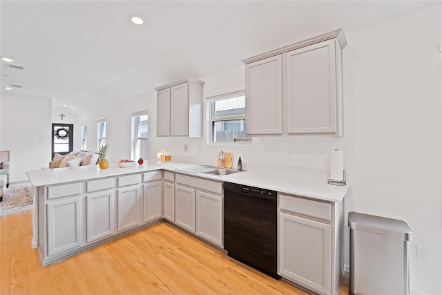 kitchen featuring black dishwasher, a sink, open floor plan, light wood-type flooring, and a peninsula
