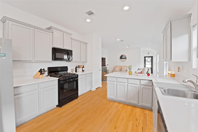 kitchen featuring visible vents, a sink, black appliances, recessed lighting, and light wood finished floors