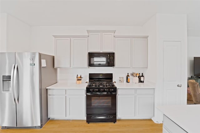 kitchen with light wood finished floors, light countertops, black appliances, and white cabinetry