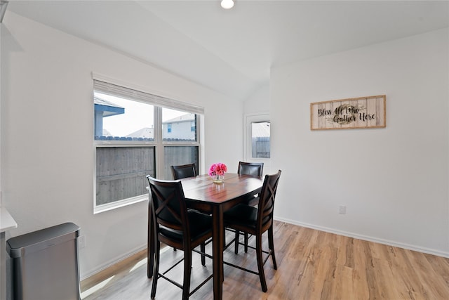 dining area featuring light wood-style flooring, baseboards, and lofted ceiling
