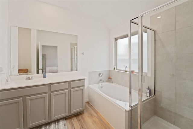 full bathroom featuring lofted ceiling, a shower stall, ensuite bath, wood finished floors, and a garden tub