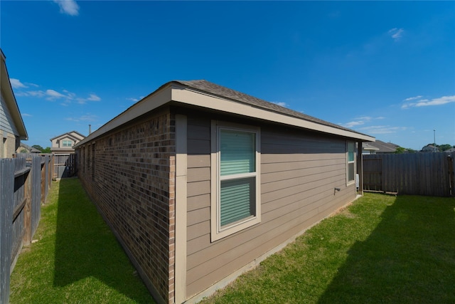 view of property exterior featuring brick siding, a fenced backyard, and a lawn