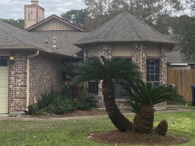 view of front facade with roof with shingles, fence, brick siding, a chimney, and a garage