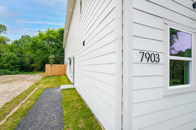 view of side of home featuring dirt driveway and fence