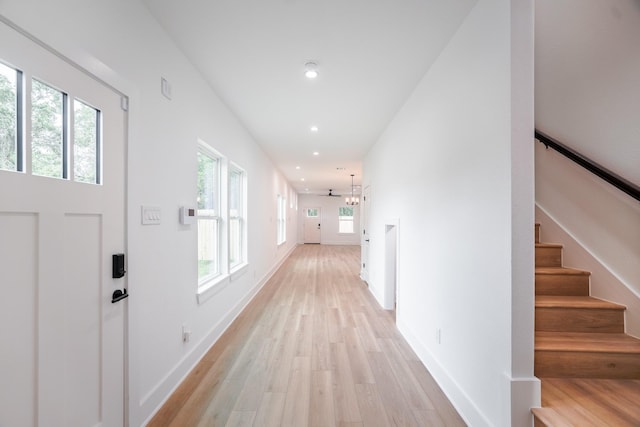 hallway featuring baseboards, recessed lighting, light wood-style floors, and stairway