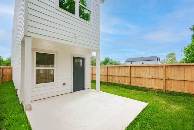 rear view of house featuring a lawn, a patio area, and a fenced backyard