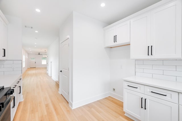 kitchen featuring recessed lighting, white cabinets, light wood finished floors, light countertops, and decorative backsplash