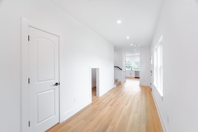 hall with light wood finished floors, baseboards, recessed lighting, and stairway