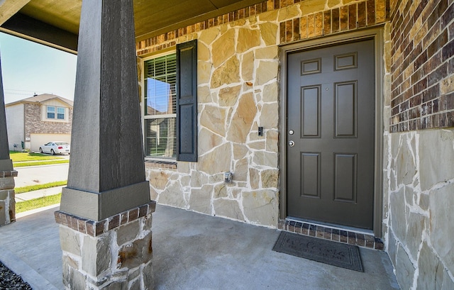 view of exterior entry with a porch and stone siding