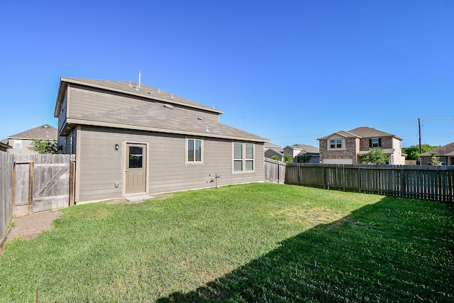 rear view of house with a fenced backyard and a lawn