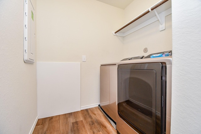 washroom with baseboards, electric panel, washer and clothes dryer, laundry area, and wood finished floors
