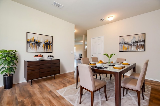 dining space featuring visible vents, baseboards, and wood finished floors