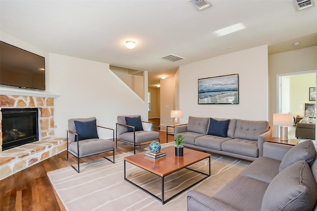 living room featuring visible vents, wood finished floors, and a fireplace