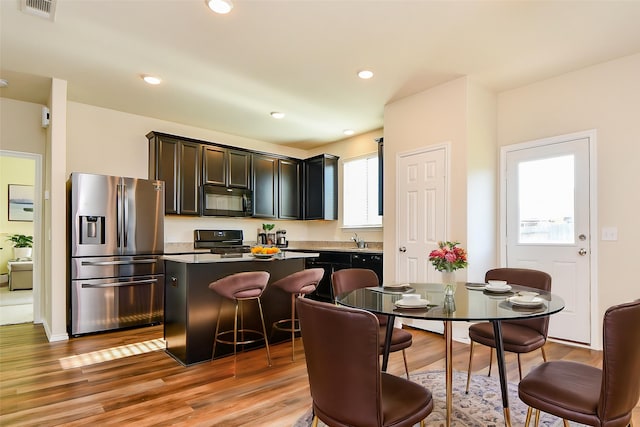 kitchen with light wood-type flooring, visible vents, black appliances, and a kitchen island
