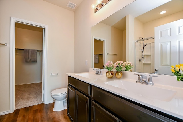 bathroom with a sink, visible vents, a shower stall, and wood finished floors