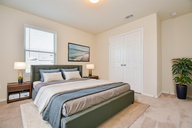 bedroom featuring a closet, visible vents, light colored carpet, and baseboards