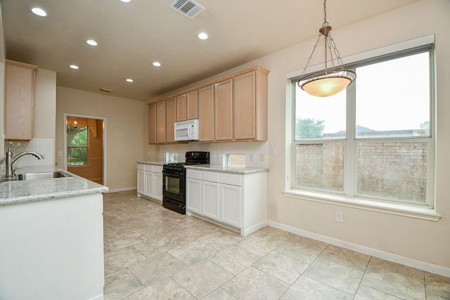 kitchen featuring white microwave, visible vents, a sink, baseboards, and black gas range