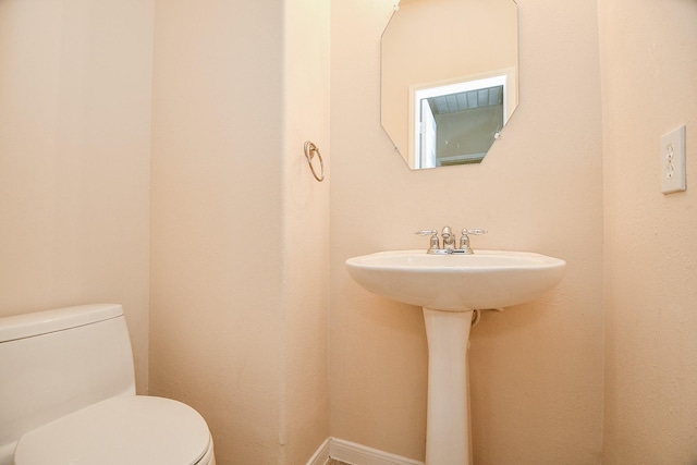 half bath with baseboards and toilet