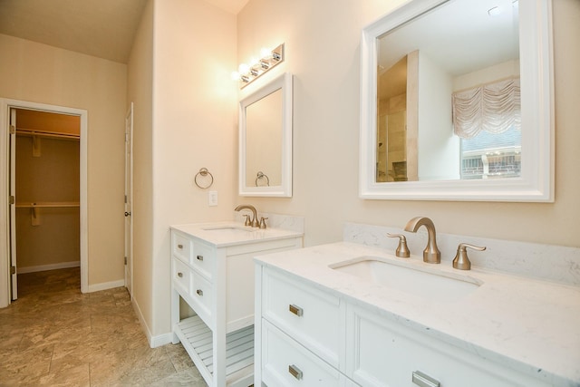 bathroom featuring a spacious closet, two vanities, and a sink