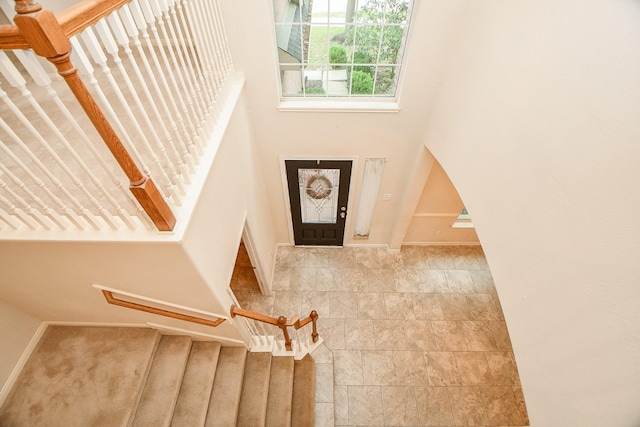 entrance foyer with stairway, a high ceiling, and baseboards