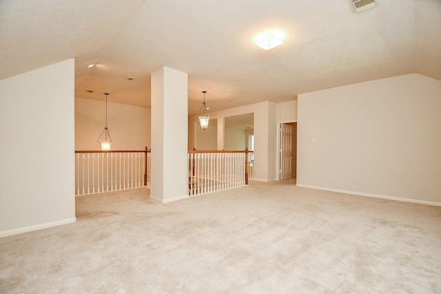 empty room featuring visible vents, light colored carpet, and lofted ceiling