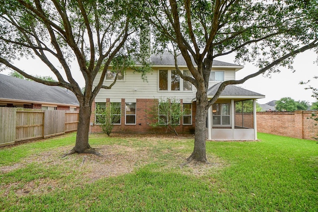 back of house featuring a fenced backyard, a sunroom, and a lawn