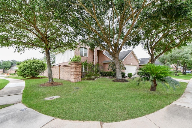 view of front of home featuring brick siding, a front yard, and a garage