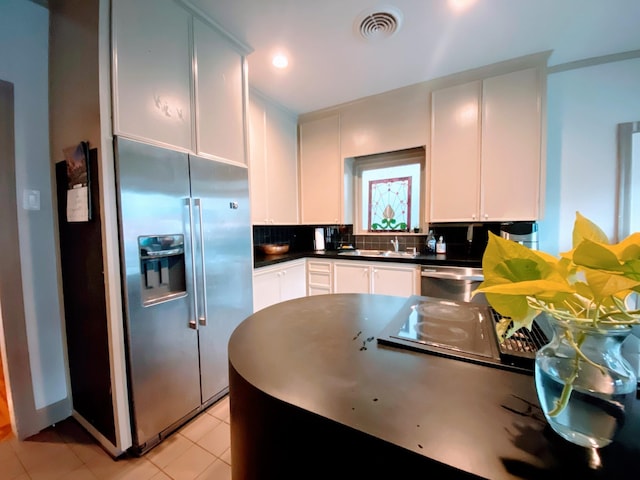1964 Norfolk St, Houston, TX 77098 - kitchen featuring appliances with stainless steel finishes, a sink, dark countertops, light tile patterned floors, and tasteful backsplash