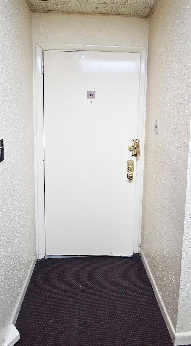 hallway with dark colored carpet and baseboards