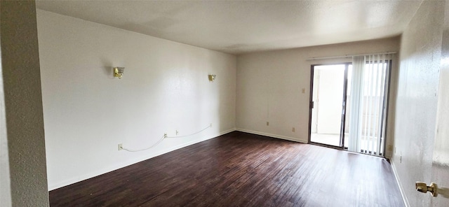 spare room featuring dark wood-style flooring and baseboards