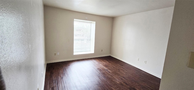 unfurnished room featuring baseboards and dark wood-style floors