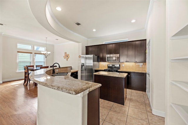 5329 Kansas St, Houston, TX 77007 - kitchen with ornamental molding, visible vents, a sink, stainless steel appliances, and a center island with sink