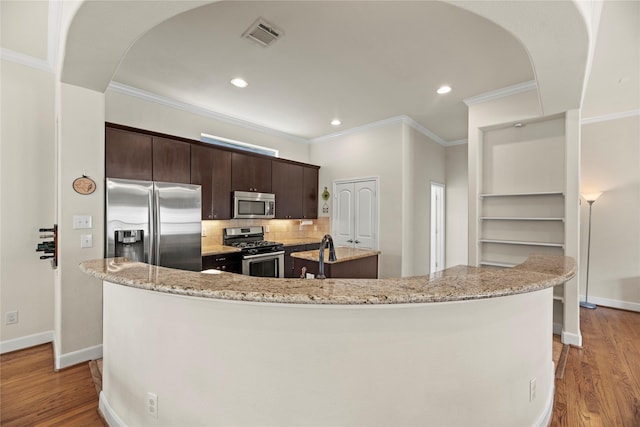 5329 Kansas St, Houston, TX 77007 - kitchen featuring dark brown cabinetry, visible vents, appliances with stainless steel finishes, a kitchen island with sink, and wood finished floors