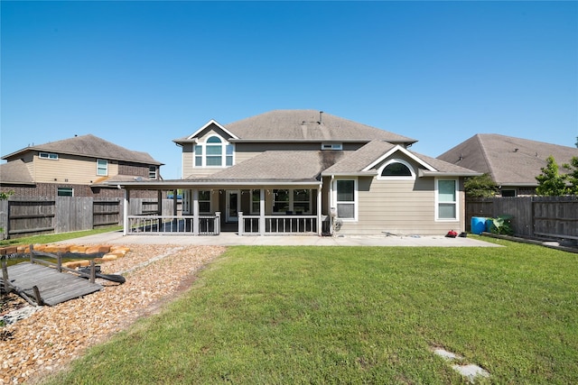 rear view of property with a sunroom, roof with shingles, a fenced backyard, and a lawn