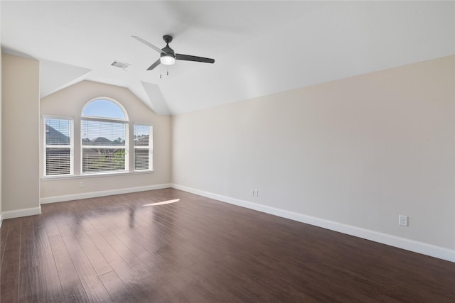 empty room featuring dark wood-type flooring, a ceiling fan, vaulted ceiling, visible vents, and baseboards
