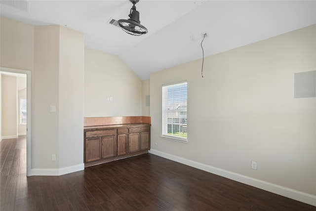 unfurnished dining area featuring visible vents, baseboards, dark wood finished floors, and vaulted ceiling