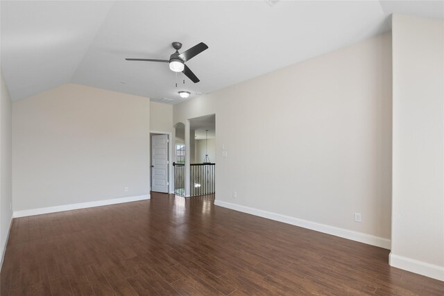 empty room with ceiling fan, baseboards, vaulted ceiling, and dark wood-style flooring