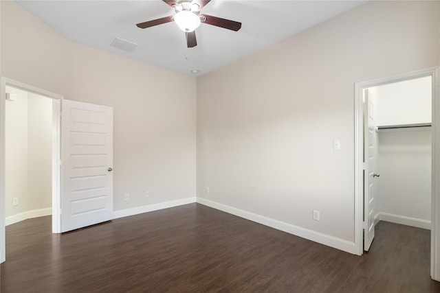 unfurnished bedroom featuring visible vents, a closet, baseboards, dark wood-style flooring, and a spacious closet