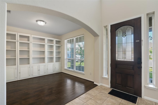 tiled foyer entrance with visible vents, baseboards, and arched walkways