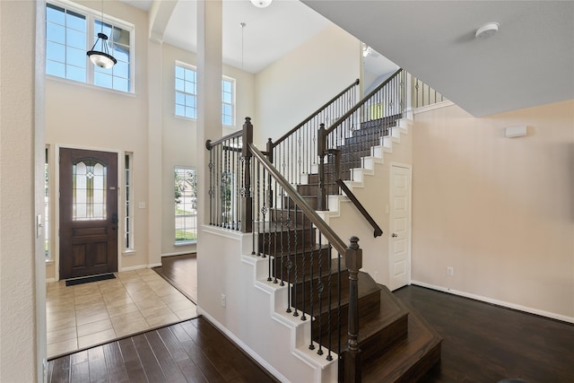 entryway with a high ceiling, baseboards, stairway, and hardwood / wood-style flooring