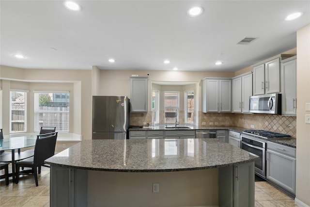 kitchen featuring visible vents, a kitchen island, gray cabinetry, and stainless steel appliances