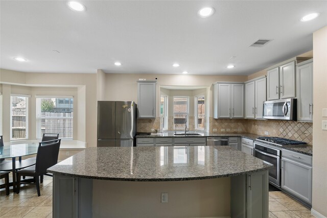 13315 Edison Trace Ln, Tomball, TX 77377 - kitchen with a center island, a healthy amount of sunlight, gray cabinets, visible vents, and appliances with stainless steel finishes