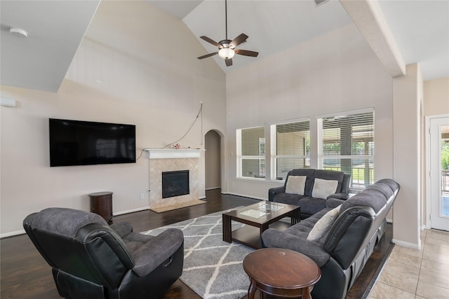 living area with a tile fireplace, high vaulted ceiling, baseboards, and a ceiling fan