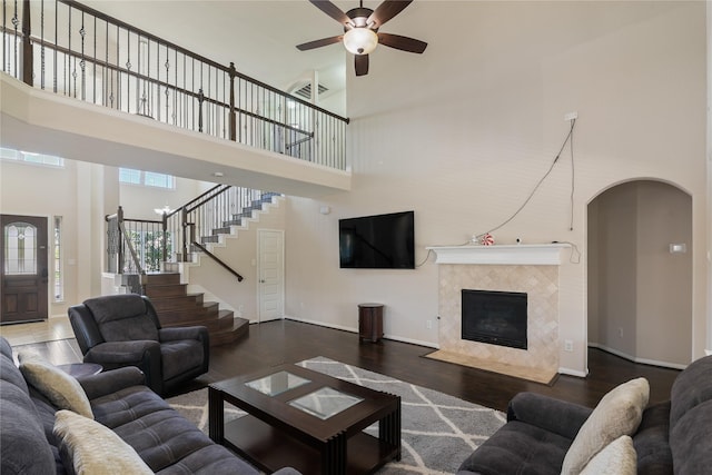 living area featuring a towering ceiling, stairs, visible vents, ceiling fan, and wood finished floors